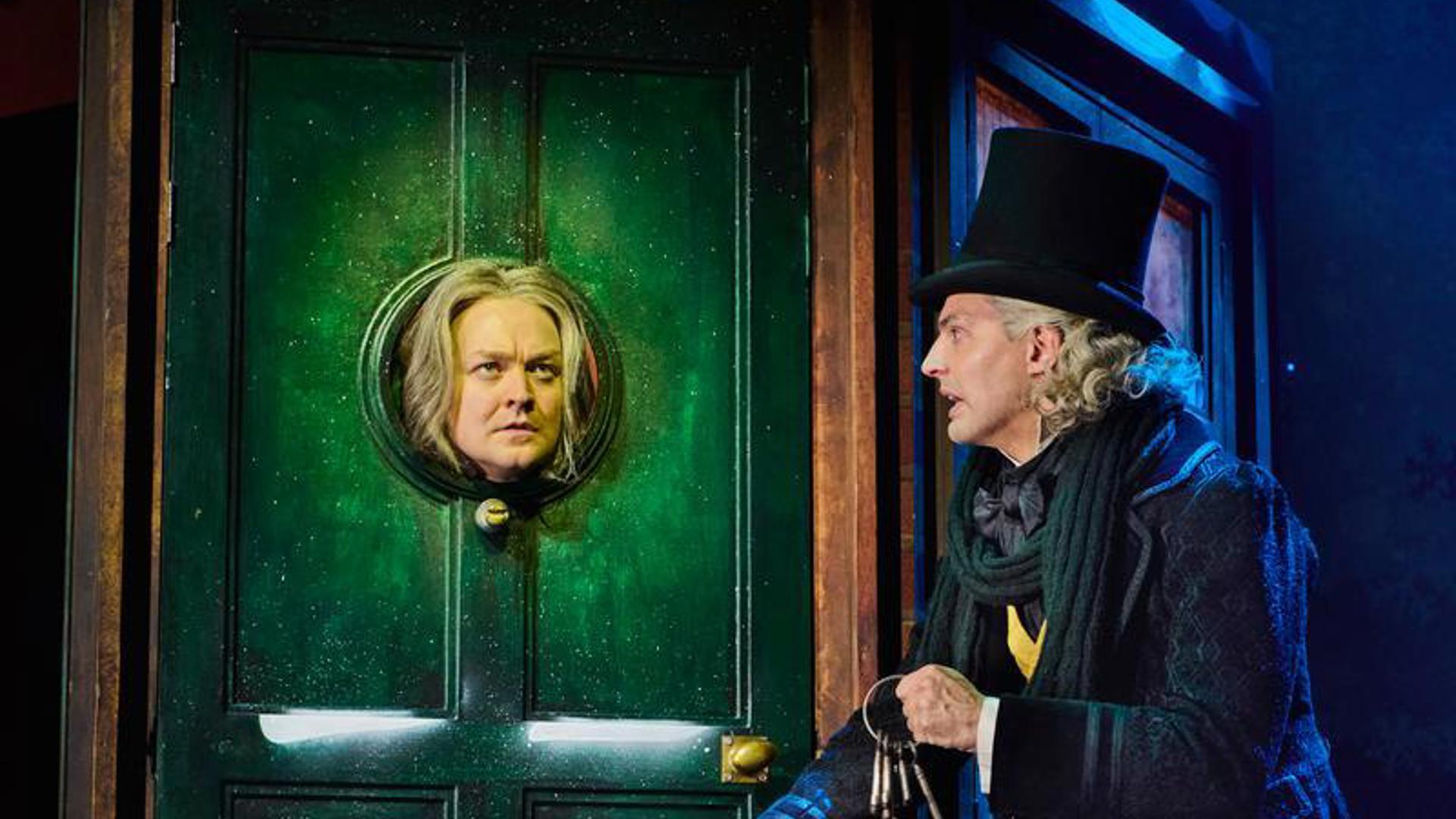 Two performers appear on stage, one with their head sticking out of a door and the other looking in at them.