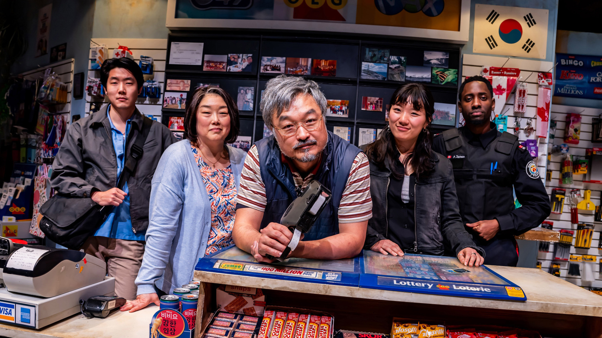 Five people pose together behind the counter of a convenience store.