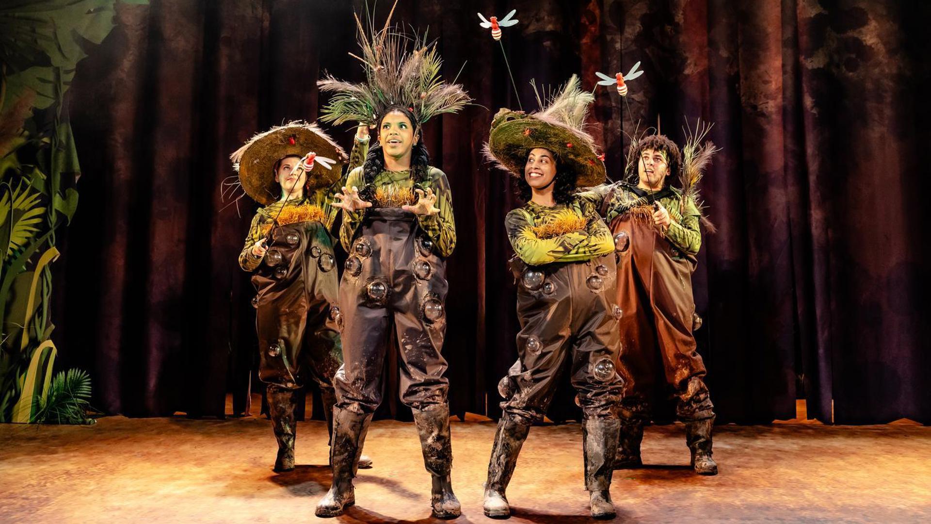 Four performers playing swampy plants with bugs around them.