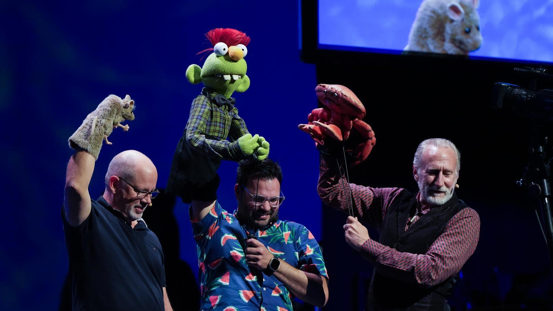 three puppeteers with puppets performing 