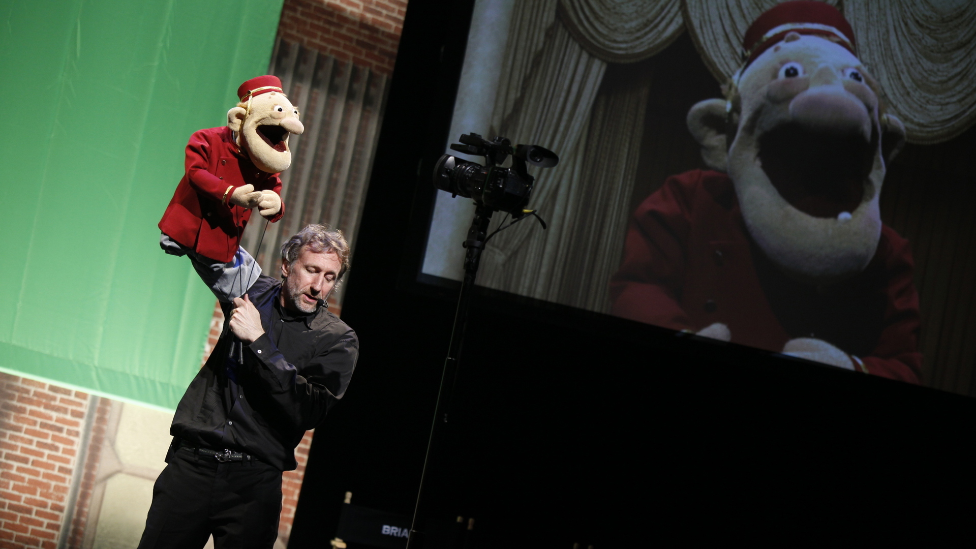 puppeteer with puppet being projected onto a big screen